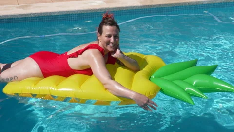 A woman is laying on a pool float shaped like a pineapple Stock Footage 278000766
