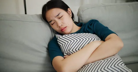 Woman leaned back on the sofa and hugged a pillow, her face showing stress. Stock-Footage 310870133