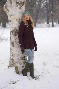 Woman leaning against tree in winter Stock Photos