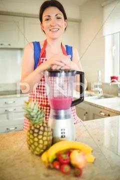 Woman Leaning Hand On Mixer In Kitchen