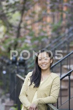 A woman leaning on a railing in a park Stock Photos