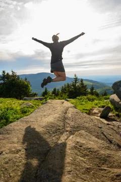 Woman Leaps Off Boulder While Looking Over Blue Ridge Mountains Foto stock