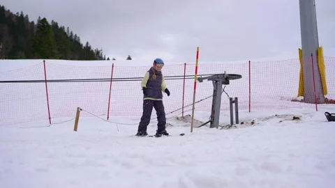 Woman is learning how to ski. She moves up the hill using a ski elevator and Stock Footage 219362524