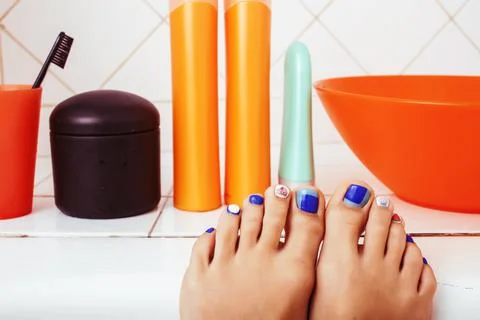 Woman legs in bathroom with lot of stylish stuff for care, pedicure creative Stock Photos