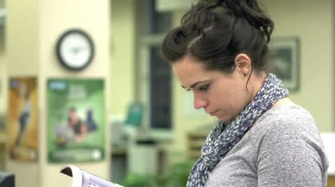 Woman in library looking at book Stock Footage