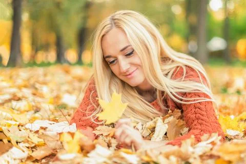 Woman lies down on leaves at the autumn park Stock Photos