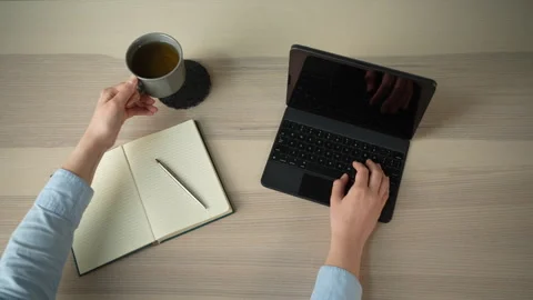 Woman lifting coffee mug while working on laptop at desk, top view Video stock 329010403
