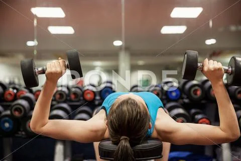 Woman lifting dumbbell weights while lying down Stock Photos