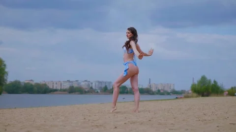 A woman in a light blue, patterned bikini strolls and relaxes on the beach Video stock 308514631