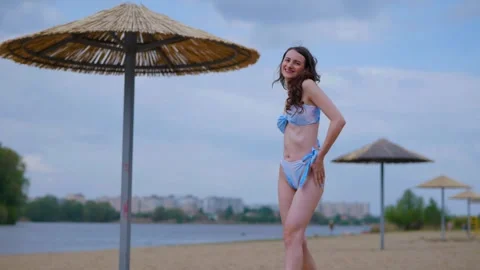 A woman in a light blue, patterned bikini strolls and relaxes on the beach Video stock 308514706