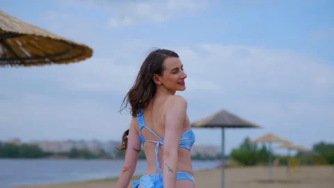 A woman in a light blue, patterned bikini strolls and relaxes on the beach Video stock 308514894