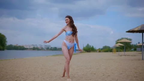 A woman in a light blue, patterned bikini strolls and relaxes on the beach Video stock 308515005