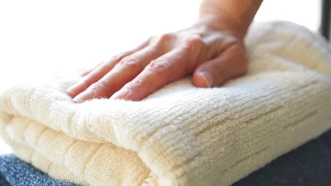 Woman lightly pressing a stack of fluffy towels with her hand Stock Footage 302026657