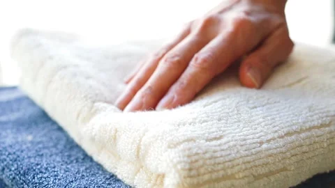 Woman lightly pressing a stack of fluffy towels with her hand Stock Footage 302026675