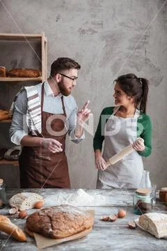 A woman listening the instructions of a man about baking bread Stock Photos