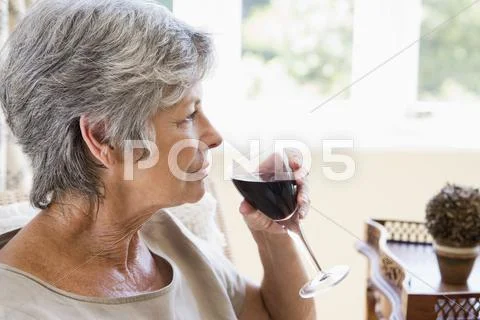 Woman in living room with glass of wine Stock Photos