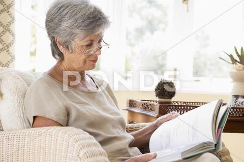 Woman in living room reading book Stock Photos