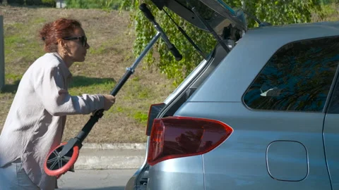 Woman loading folding scooter into car trunk Stock Footage 344927082