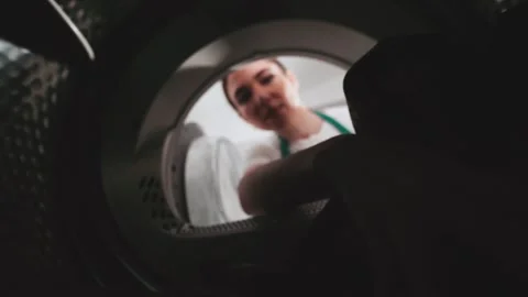 Woman loading laundry into washing machine at a laundry facility during daytime Stock Footage 305281252