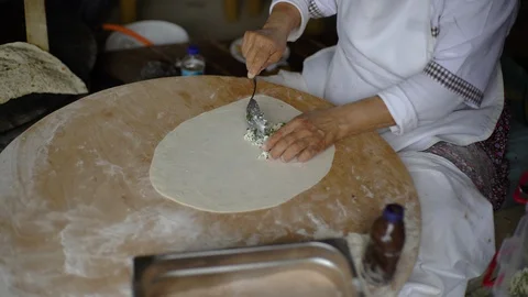A woman is loading stuffing into a pancake, cheese, meat, potatoes. Stock-Footage 91015276