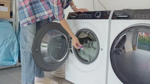 Woman loading towels and detergent capsule into washing machine Vídeos de archivo 345006982
