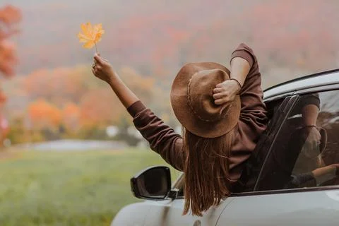 Woman with long hair in brown hat and shirt looking out from white car Stock Photos