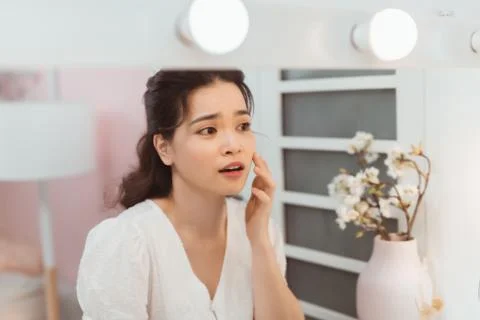 Woman look mirrior feel upset and touch her face with acne problem Stock Photos