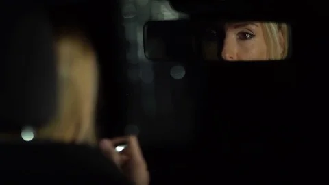 Woman looking and correcting make-up in rear view mirror in the car. Close up. F Stock Footage 80252642