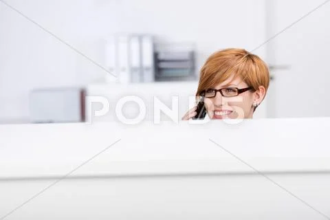 Woman looking away while on call in office cubicle Stock Photos