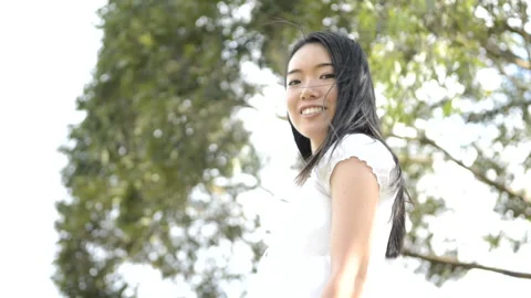 Woman looking back in front of a tree swaying Stock Footage 160160007