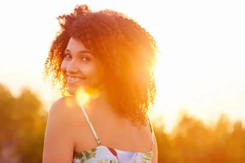 Woman looking back over her shoulder with sun flare Stock Photos