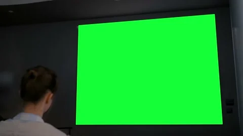Woman looking at blank large interactive wall display - green screen concept Video stock 135055213