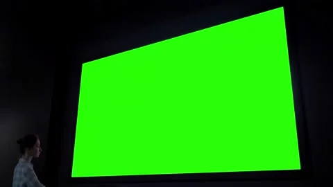 Woman looking at blank large interactive wall display - green screen concept Video stock 146367018