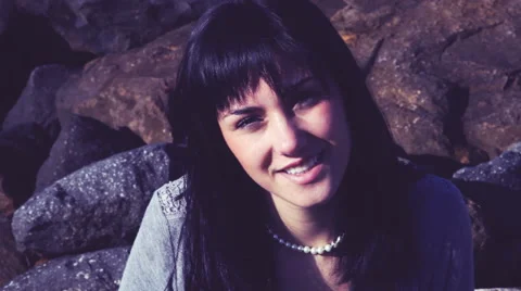 Woman looking camera sitting on rocks retro style closeup Stock Footage 46053157
