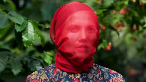 Woman looking at camera while standing near green leaves fluttering Stock Footage 161038320