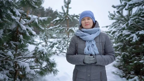 Woman looking at camera while walking among pine trees in snowy winter forest Stock Footage 102035629
