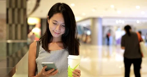 Woman looking at cellphone and holding coffee Stock Footage