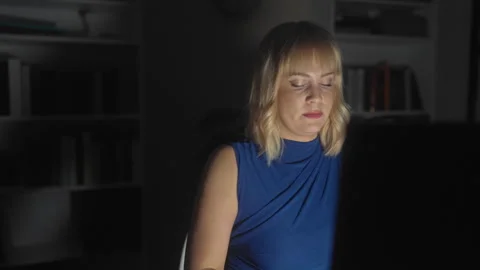 Woman looking down at computer screen in studio, face lit by monitor glow a.. Stock Footage 337386252
