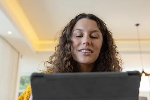 Woman looking down at tablet while holding dark case, wearing mustard-yellow Stock Photos