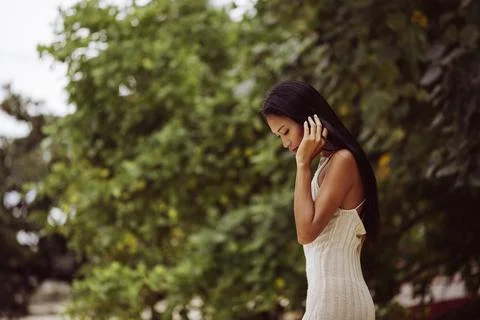 Woman looking down while gently touching her hair in quiet setting Stock Photos