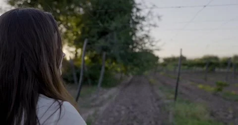 Woman looking at an empty field that will soon be sown. Vineyard has no grapes Stock Footage 156300107