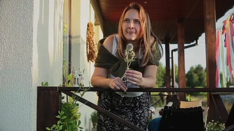 Woman looking at globe thistle while leaning on railing during sunny day Stock Footage 168842584