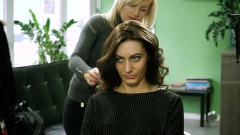 A woman looking at her reflection in the mirror on hair shaped into a style. HD 库存影片 73135636
