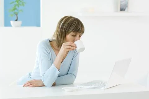 Woman looking at laptop computer, drinking coffee Foto stock