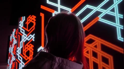 Woman is looking at LED columns with immersive geometric show on screen walls Stock Footage 339775697