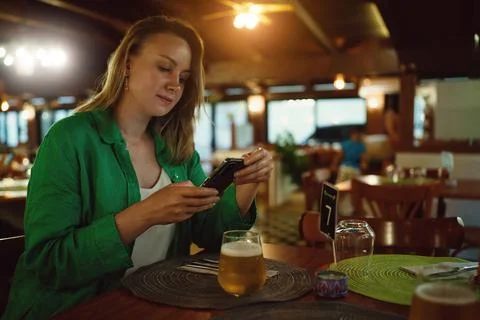 Woman is looking at menu via qr code in restaurant. Stockfoto's