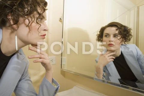 Woman Looking In Mirror With Hand On Chin