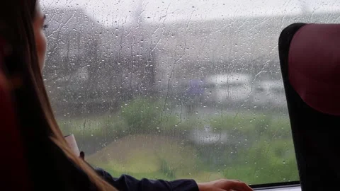 Woman Looking Out Train Window on Rainy Day – Raindrops in Focus Stockbeeldmateriaal 314534667