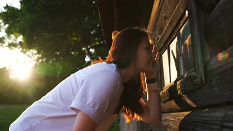 Woman looking out the window of an old wooden house in a suburban complex Stock Footage 160143950