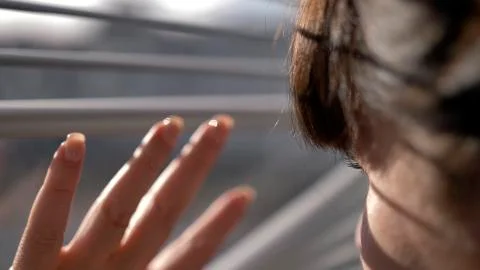 Woman looking out the window through the blinds and waving Stock Photos